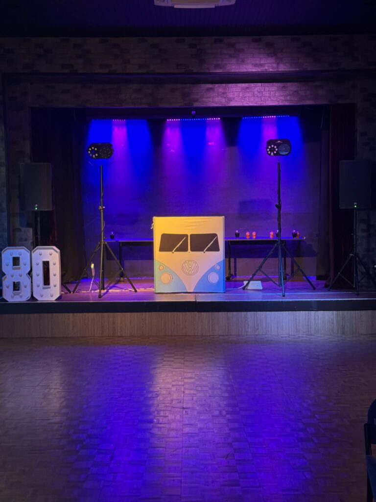     Party DJ Hire setup for an 80th birthday celebration with professional DJ booth, sound system and lighting